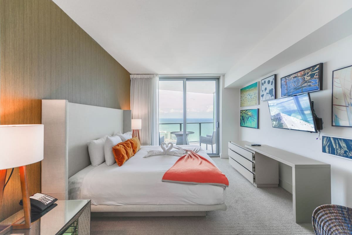 Une chambre d’hôtel moderne avec un grand lit, un bureau et une vue sur l’océan.