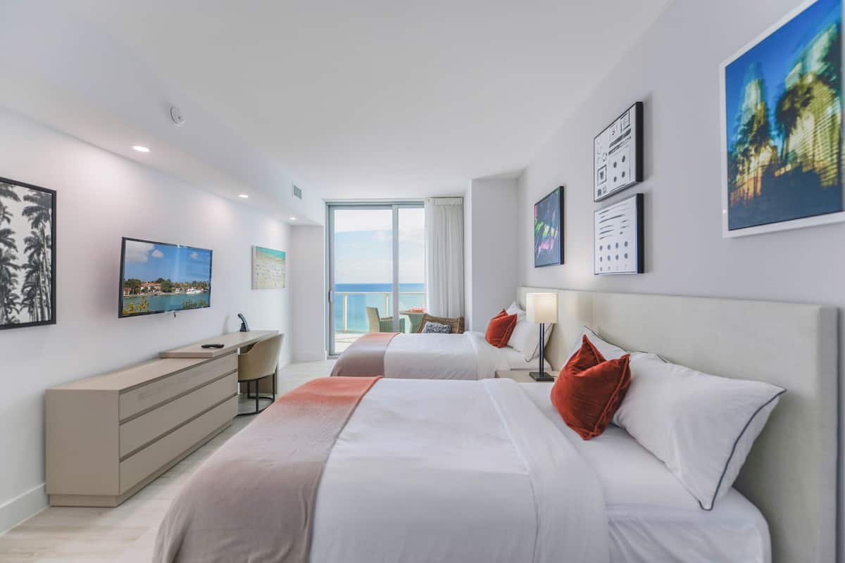 Une chambre d’hôtel moderne avec deux lits, un bureau et une vue sur la mer.