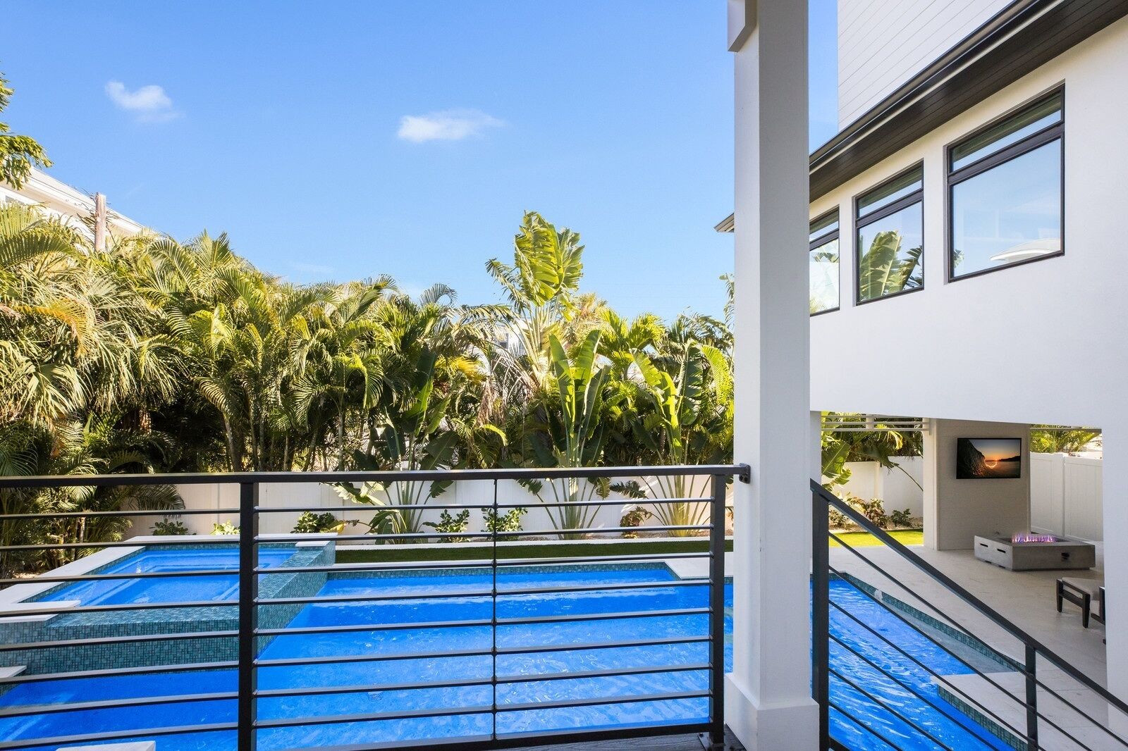 A modern building with a pool area, surrounded by lush tropical vegetation.
