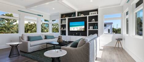 A modern living room with a large TV, two sofas, and a coffee table.