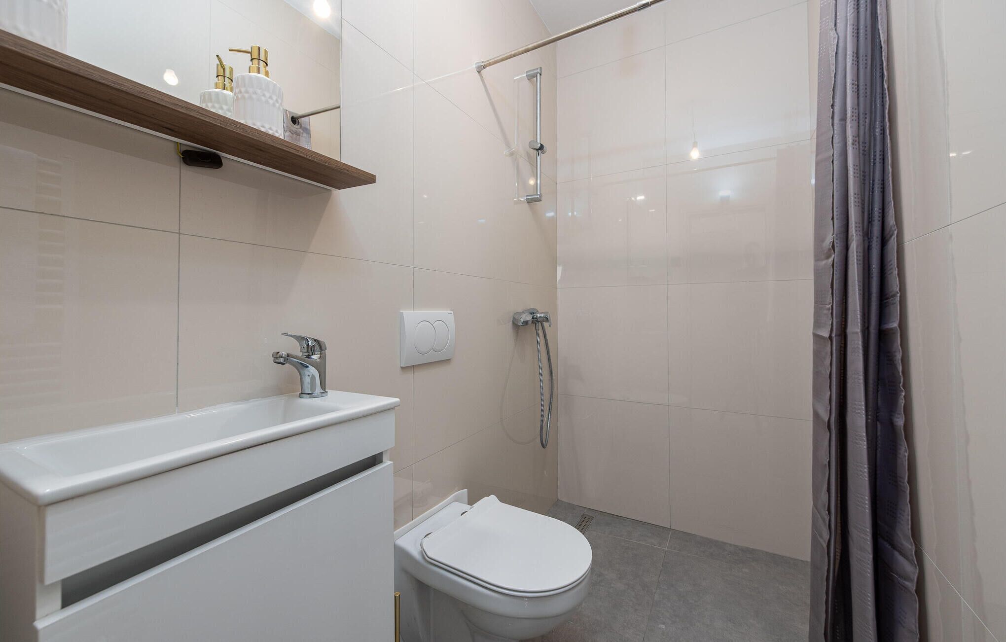 A modern bathroom with a white sink, a toilet, and a shower.