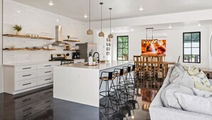 A modern kitchen with white cabinetry, a central island, and hanging pendant lights. - The Sand Hollow Retreat #h8 7 Bedroom Home (Hurricane)