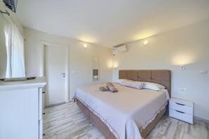 A bedroom with a bed, a nightstand, a mirror, and a door. - Recently Built, Cosy Retreat for Two, A/C, Private Pool with Superb Views over the Konavle Valley! (Dubravka)