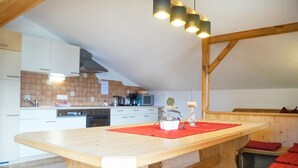 Una cocina moderna con armarios blancos, una mesa de madera con un mantel individual rojo y una lámpara colgante.