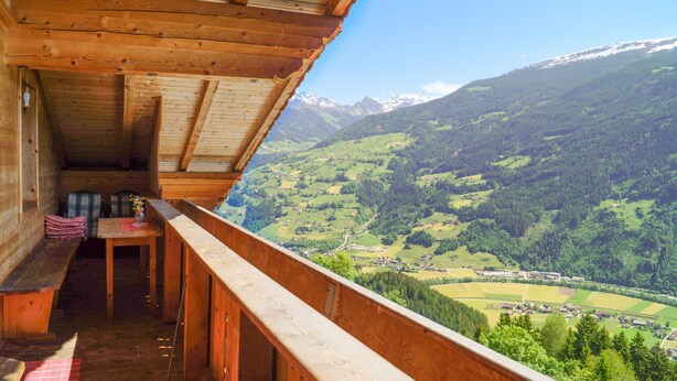 Una cabaña de madera con balcón que da a un paisaje montañoso.