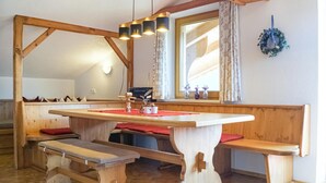 Una mesa de madera con bancos, estructura de vigas de madera y una ventana con cortinas.