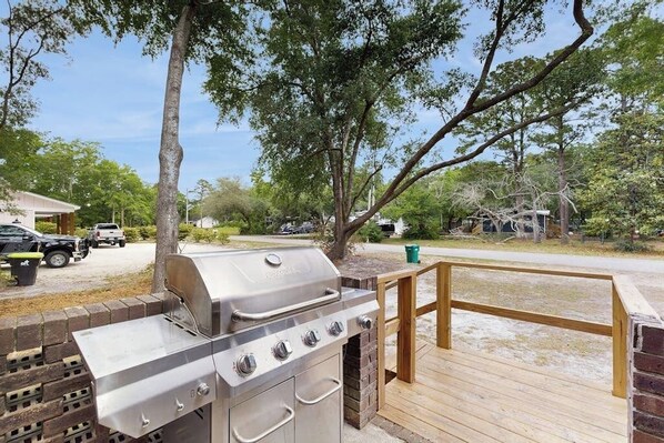 A barbecue grill with a chimney, a wooden deck, and a brick wall.