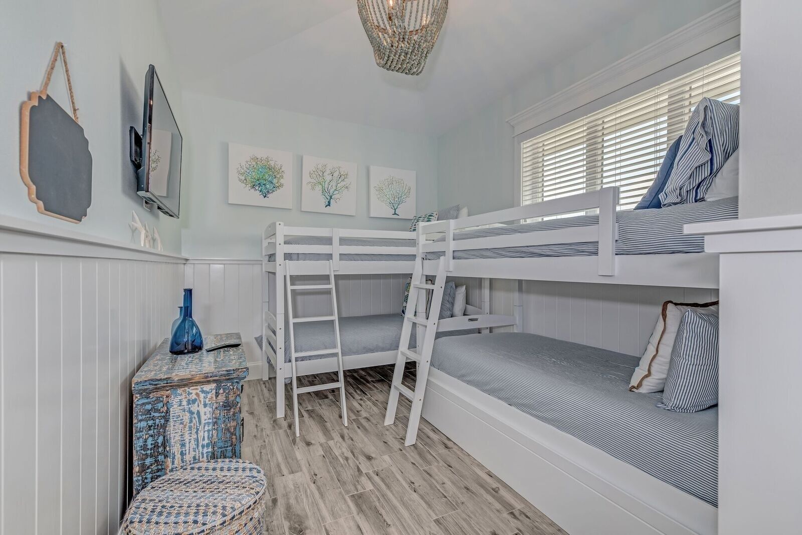 Habitación con literas, una mesita pequeña y una ventana con persianas.