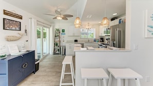 A modern kitchen with white cabinetry, a central island, and pendant lighting. - Salt Air East managed by Beach Retreats (Holmes Beach)