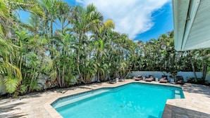 A swimming pool surrounded by lush tropical plants and a white fence. - Salt Air East managed by Beach Retreats (Holmes Beach)