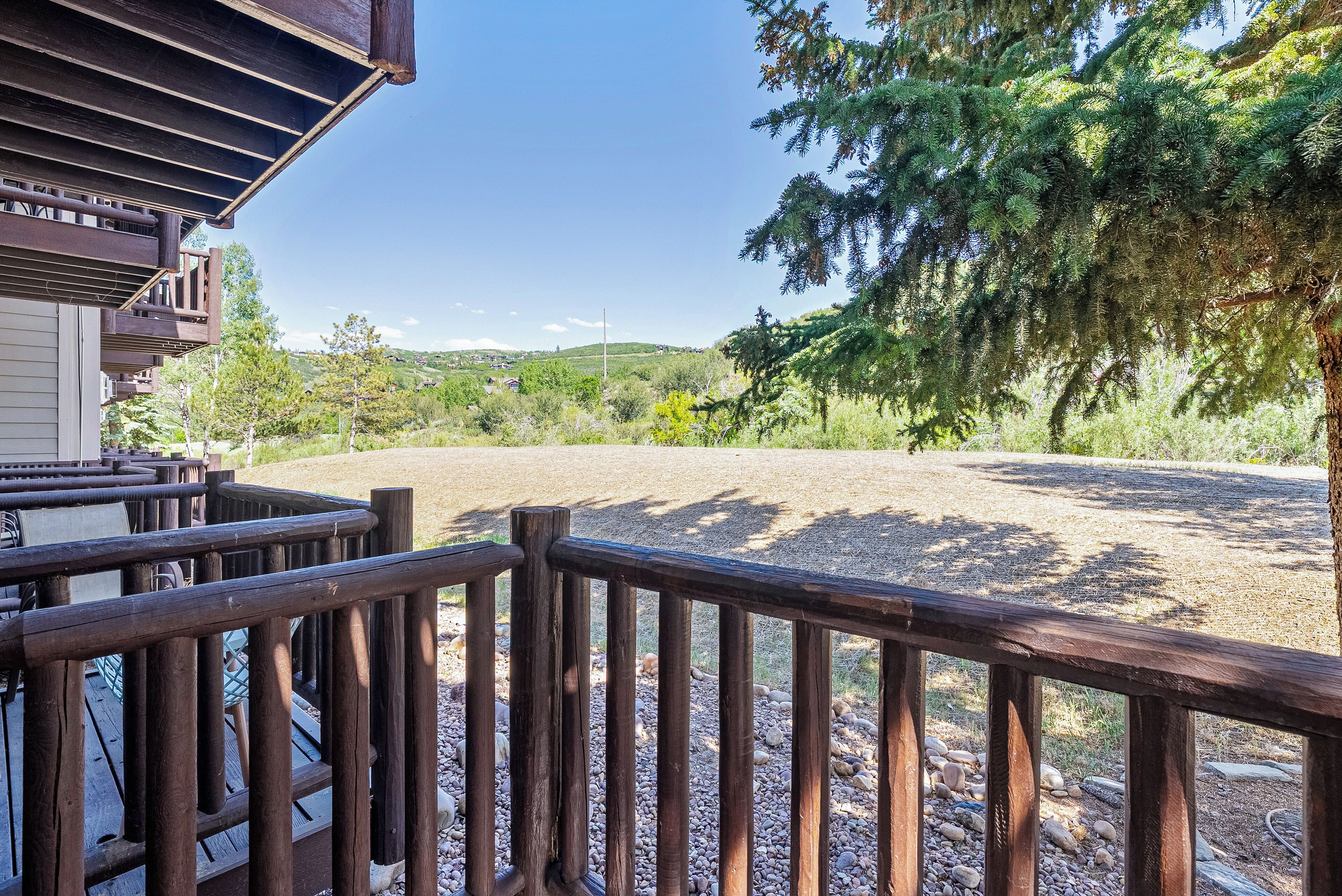 Una terraza de madera con vistas a un área de grava y árboles.
