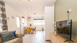 A modern living room with a sofa, TV, and dining area. - Seaside House (Great Yarmouth)