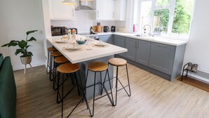A modern kitchen with a central island, bar stools, and pendant lighting. - 6 Hillside Cottages (Gainsborough)