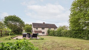 A two-story house with a tiled roof, surrounded by a grassy yard and dense foliage. - 6 Hillside Cottages (Gainsborough)