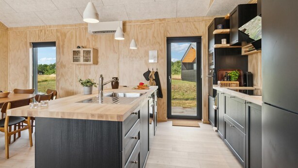 Eine moderne Küche mit Kochinsel, Holzschränken und Blick ins Freie.