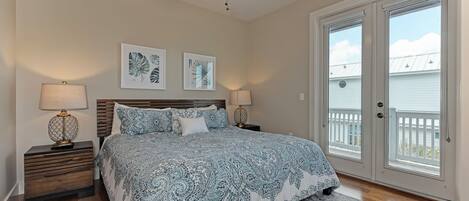 A bedroom with a bed, two nightstands, a ceiling fan, and a large sliding glass door leading to a balcony.