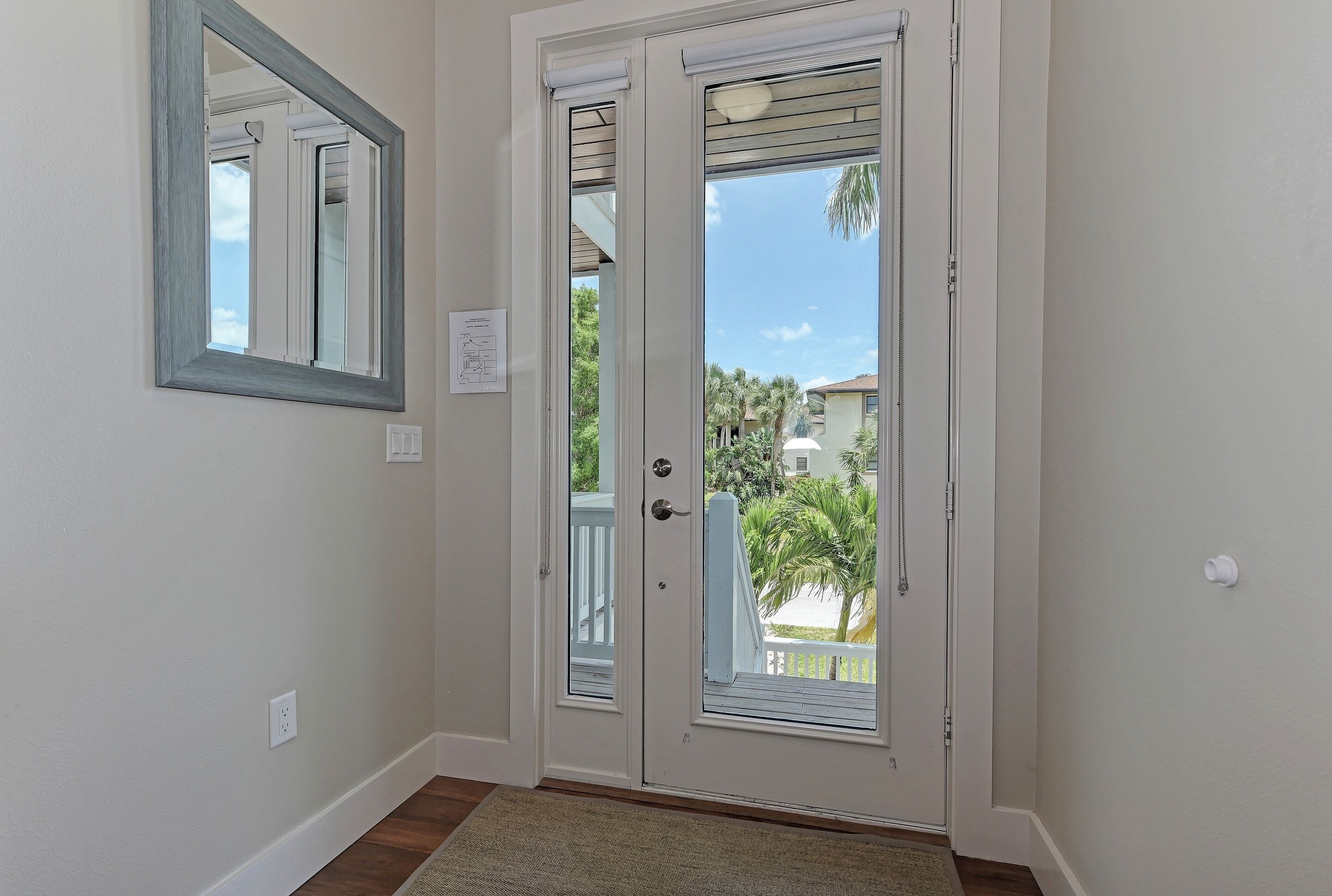 A door with a glass panel, a white wall, and a mirror above it.