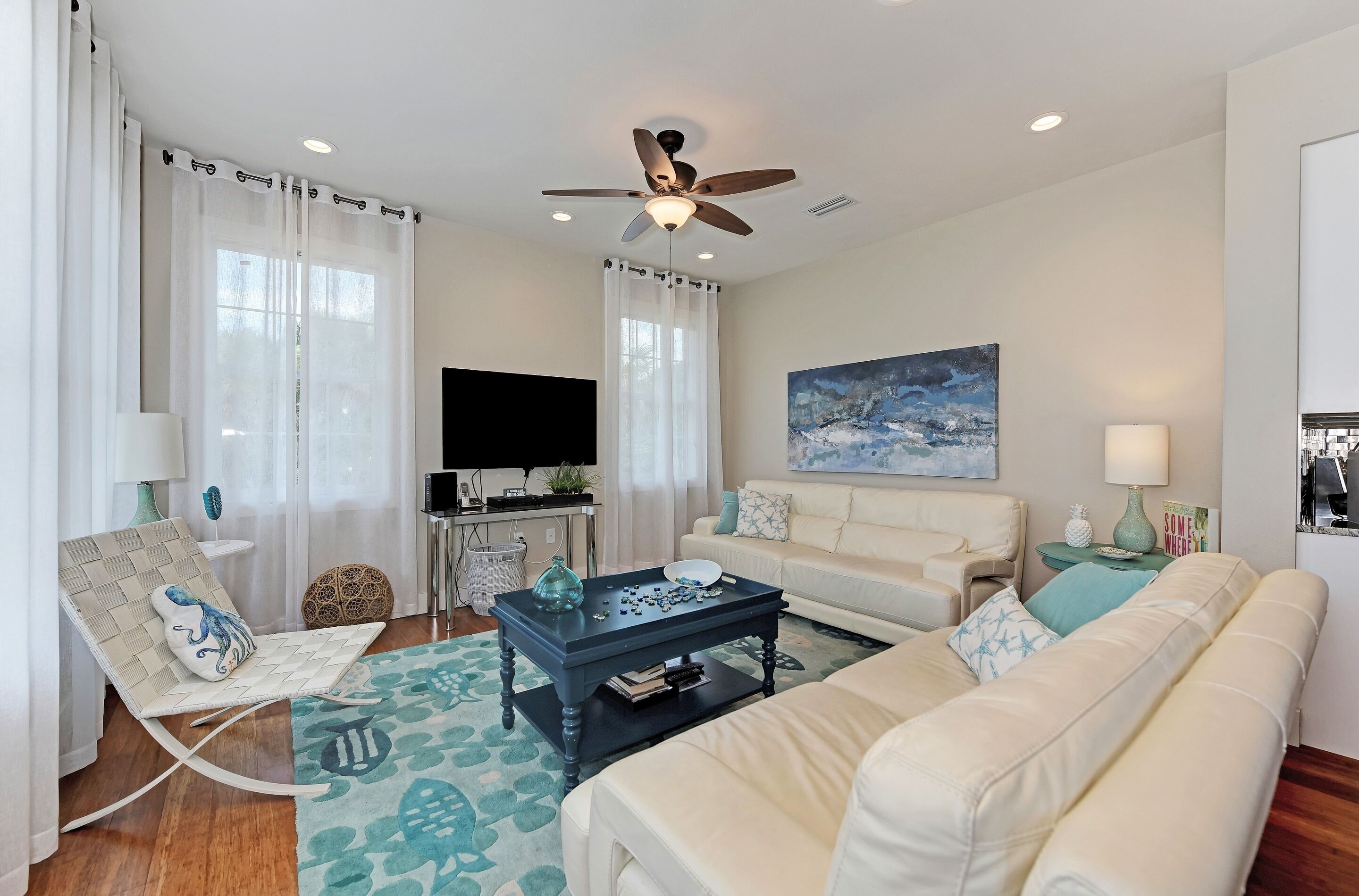A living room with a sofa, a coffee table, a TV, and a ceiling fan.