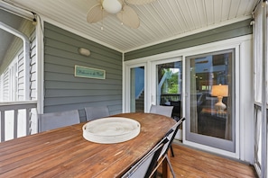A wooden deck with a table and chairs, a ceiling fan, and a sliding glass door. - 4e Windermere By The Sea 4 Bedroom Villa (Myrtle Beach)