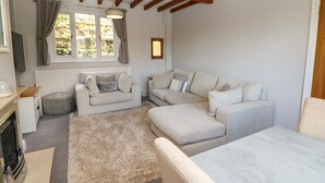 Ein gemütliches Wohnzimmer mit Kamin, zwei Sofas, einem Couchtisch und einem großen Fenster mit Vorhängen.