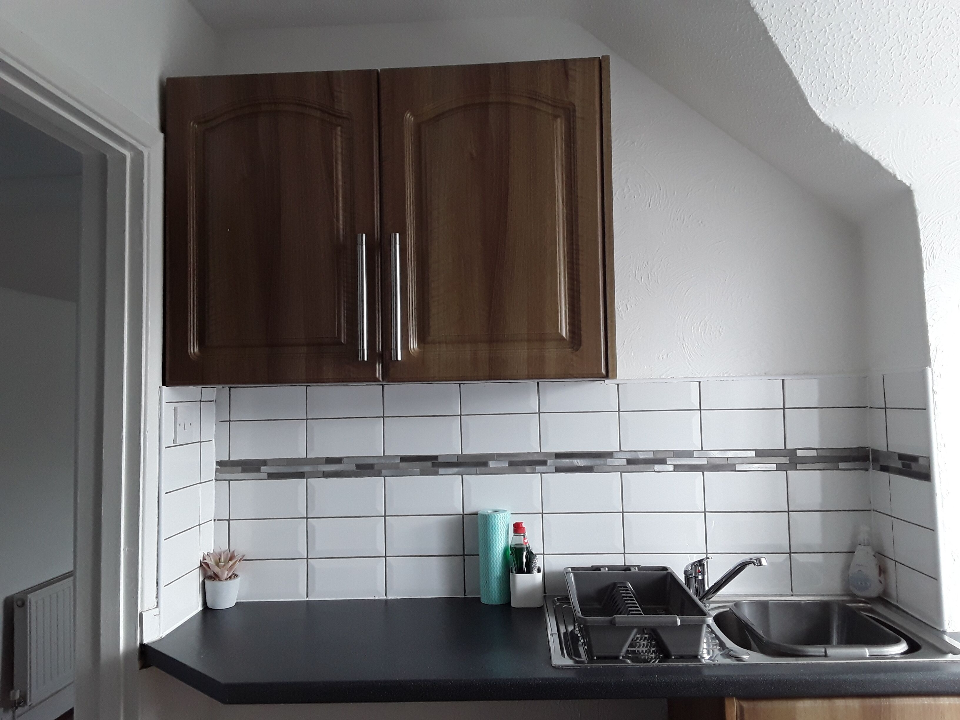 A kitchen with dark wooden cabinets, a black countertop, and a tiled backsplash.