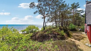 A coastal path with a view of the sea, surrounded by trees and a red building. - Cozy home in Nexø with kitchen (Nexø)