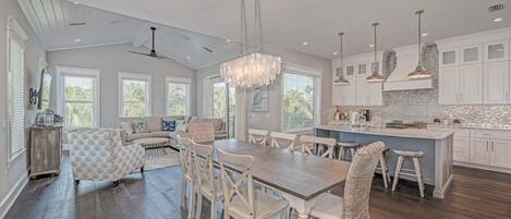 A spacious kitchen with a dining area, large windows, and a ceiling fan.