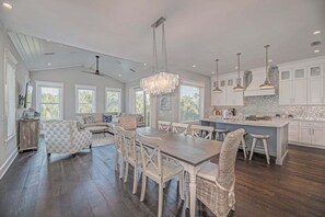 A spacious kitchen with a dining area, large windows, and a ceiling fan. - Vitamin Sea managed by Beach Retreats (Anna Maria)