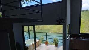 Une cuisine moderne avec vue sur un lac et un espace patio doté d’un jacuzzi et de plantes en pot.
