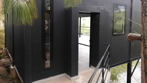 Un bâtiment moderne à l’extérieur noir, doté d’une porte bien visible et d’une fenêtre.