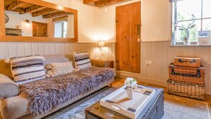 Un accogliente soggiorno con soffitto in legno, un divano con cuscini decorati, un tavolino con una lampada e una finestra con un ornamento a forma di cervo.