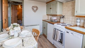 Una cucina compatta con zona pranzo, con decorazione a forma di cuore, un fornello e una lavastoviglie.