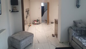 A hallway with a dog bed, a small dog, and a bowl on the floor. - The Hawthorns Large Detached 3 Bedroom Family Home (Seaham)