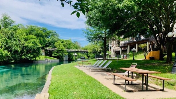 Un parque junto al río con mesas de picnic y sillones.