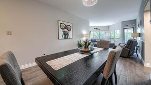 Un comedor con una mesa de madera oscura, sillas acolchadas, un centro de mesa con planta decorativa y una lámpara colgante.