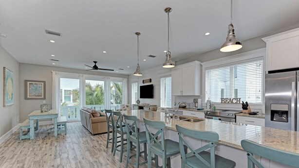 A spacious kitchen with a central island, bar stools, and a ceiling fan. - Mermaid's Landing managed by Beach Retreats (Bradenton Beach)