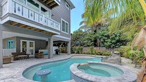 A two-story house with a backyard swimming pool, outdoor furniture, and tropical plants. - Mermaid's Landing managed by Beach Retreats (Bradenton Beach)