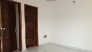 A room with two wooden doors, white walls, and a marble floor.