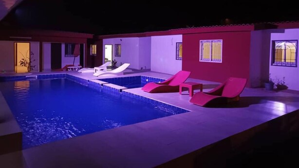 A swimming pool with lounge chairs and a door leading to the interior.