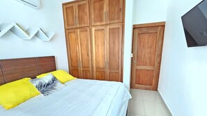 Une chambre à coucher avec un lit, une armoire en bois et un téléviseur.