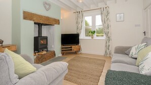A cozy living room with a fireplace, a television, and comfortable seating. - Carvannel Cottages (Camborne)