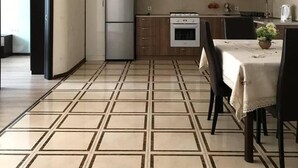 A modern kitchen with white cabinets, a stainless steel refrigerator, a gas stove, and a dining area with a table and chairs. - Nearby Chavchavadze ave Sunny Home With Balcony (Tbilisi)