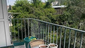 A balcony with a round table and wicker chairs, surrounded by a metal railing. - Nearby Chavchavadze ave Sunny Home With Balcony (Tbilisi)
