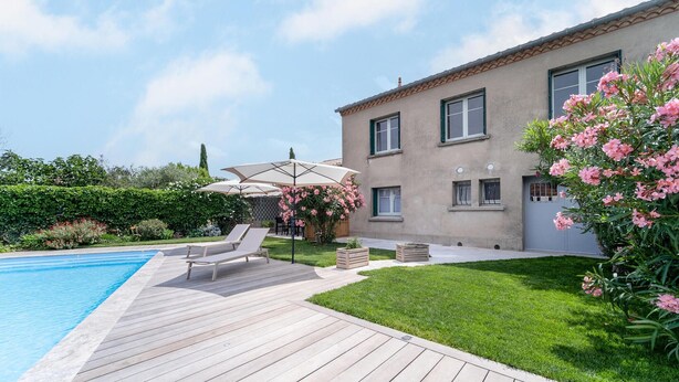 A poolside area with a wooden deck, lounge chairs, and a covered seating area with an umbrella. - Cozy home in Villegly with heated swimming pool (Villegly)