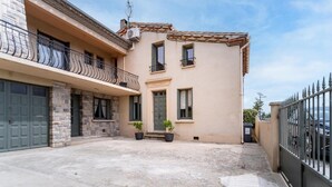 A two-story building with a stone facade, a balcony with wrought iron railings, and a small courtyard with potted plants. - Cozy home in Villegly with heated swimming pool (Villegly)