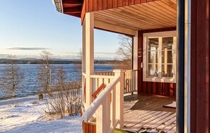 A wooden cabin with a porch overlooking a frozen lake and distant mountains. - Gorgeous home in Hunge with lake view (Hunge)