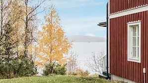 Een rood gebouw met een wit raam, omringd door bomen en gras.