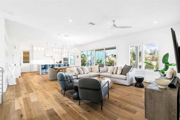 A spacious living area with a large sofa, two armchairs, a coffee table, and a dining table.