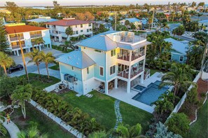A multi-story residential building with a pool, surrounded by palm trees and other greenery.