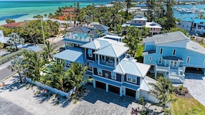Un área residencial costera con varias casas, algunas con techos azules, y una vista despejada del océano.